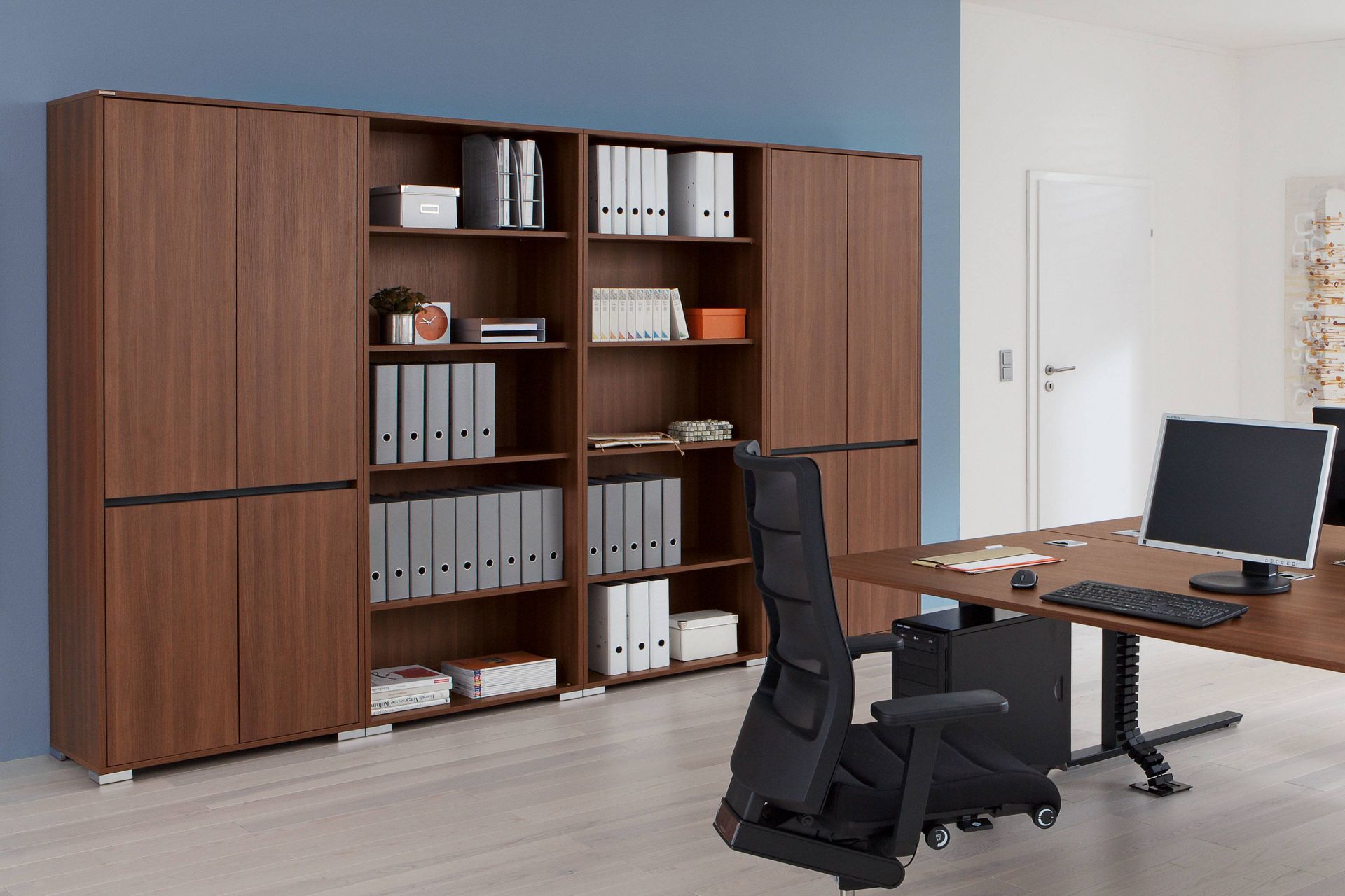 Büro mit Palmberg Garderobenschrank in Holzoptik, Regalen und Büromaterial für die Büroorganisation.