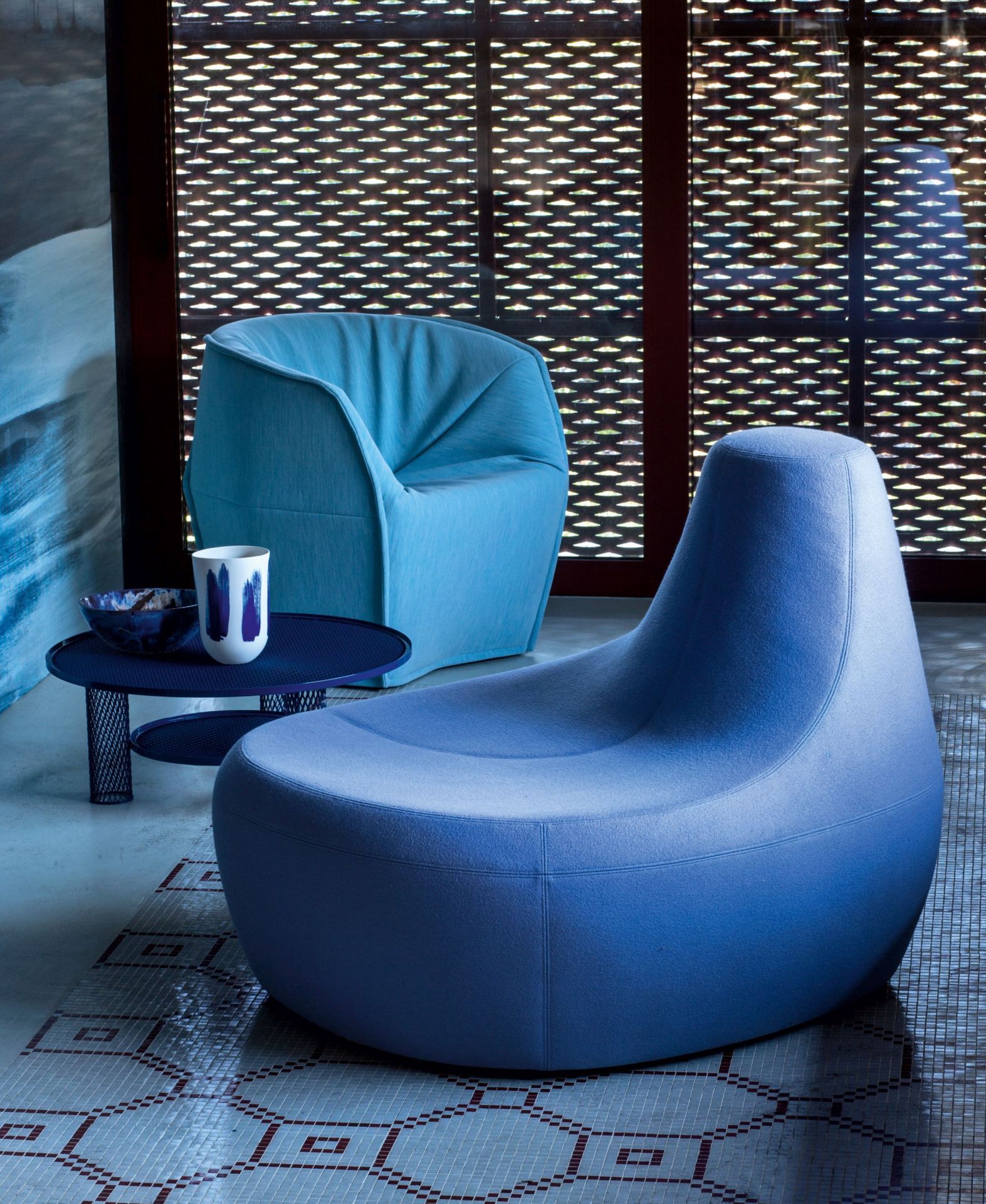 Blauer Net Beistelltisch von Moroso neben einem Sessel und Deko-Elementen im modernen Wohnzimmer.