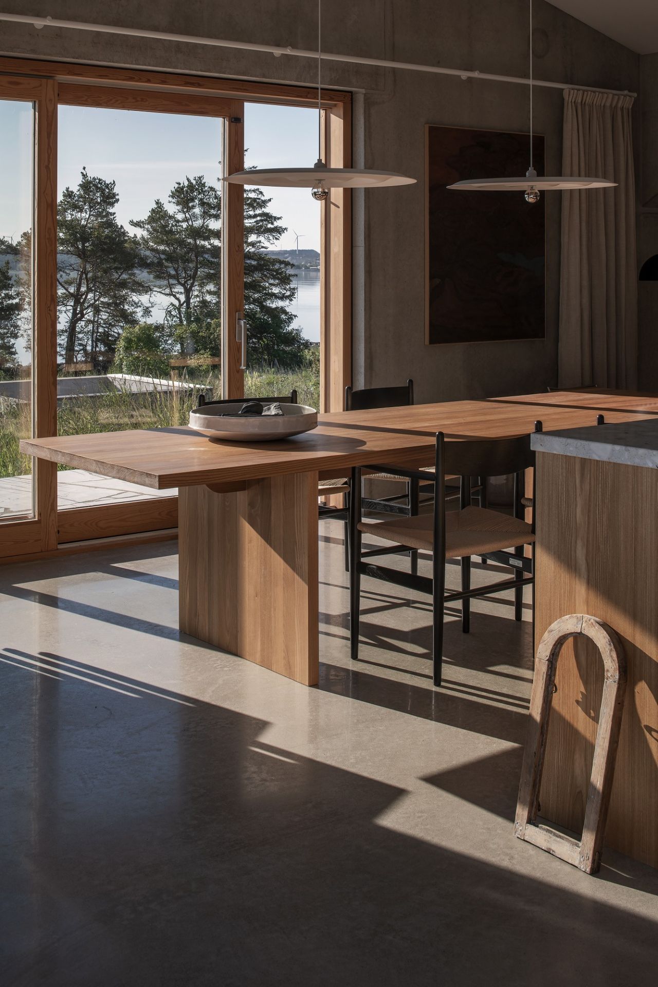 Helle w171 Alma Pendelleuchten über Esstisch aus Holz in modernem Interieur mit Seeblick.