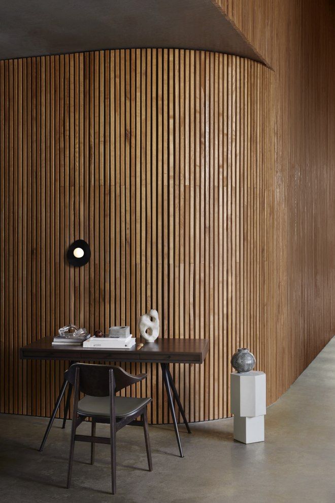 NORR11 Bufala Dining Chair Stuhl aus dunklem Holz mit Lederbezug vor einer Holzvertäfelung.