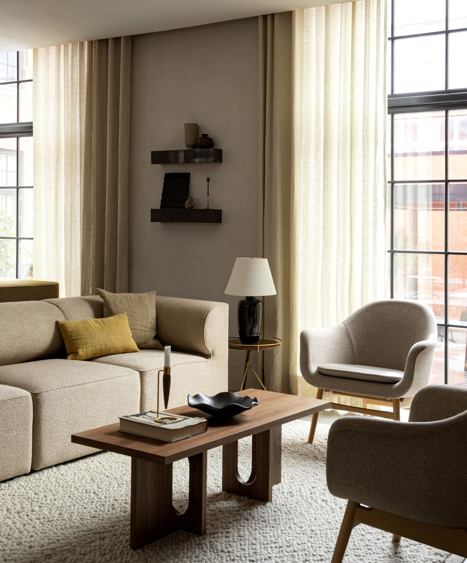 Androgyne Couchtisch von Audo Copenhagen im Wohnzimmer mit Sofa, Sessel und Teppich.