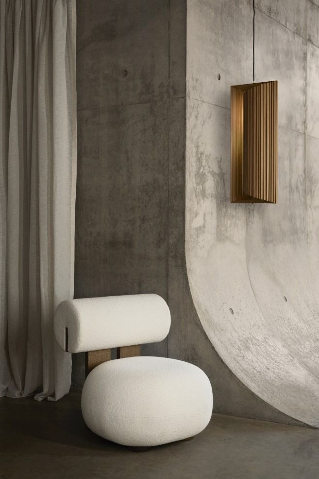 Hippo Lounge Chair Sessel NORR11 in Weiß vor Betonwand mit Lampe und Vorhang.