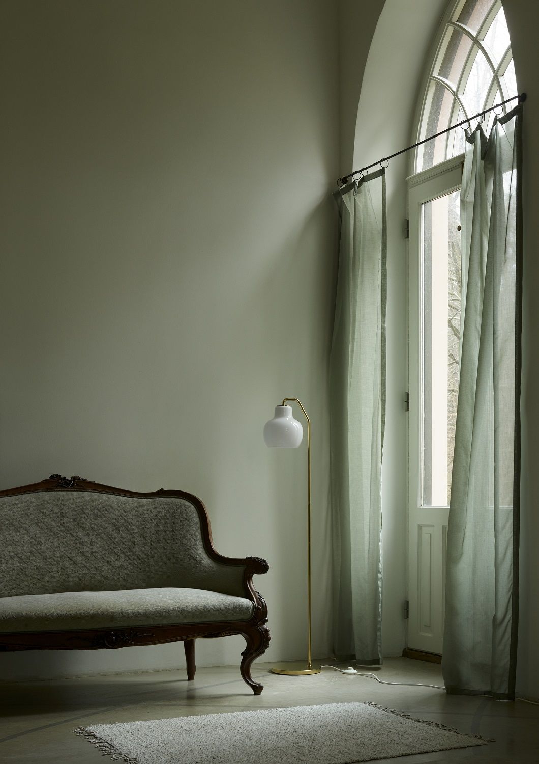 VL Ring Crown Stehleuchte von Louis Poulsen neben Sofa und Fenster mit Vorhängen.