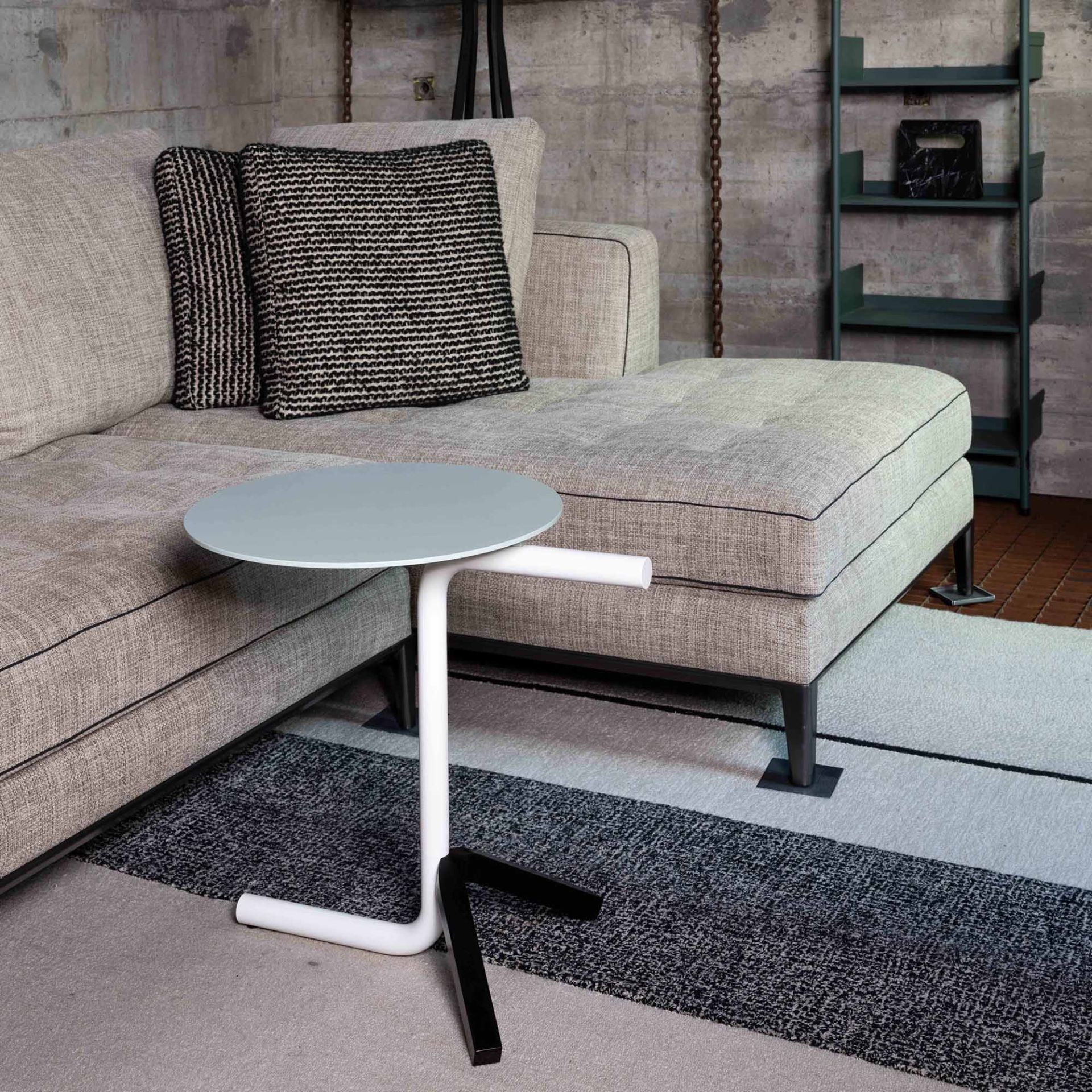 Aso Beistelltisch von Mox, runder Tisch mit weißem Gestell und grauer Tischplatte neben Sofa.