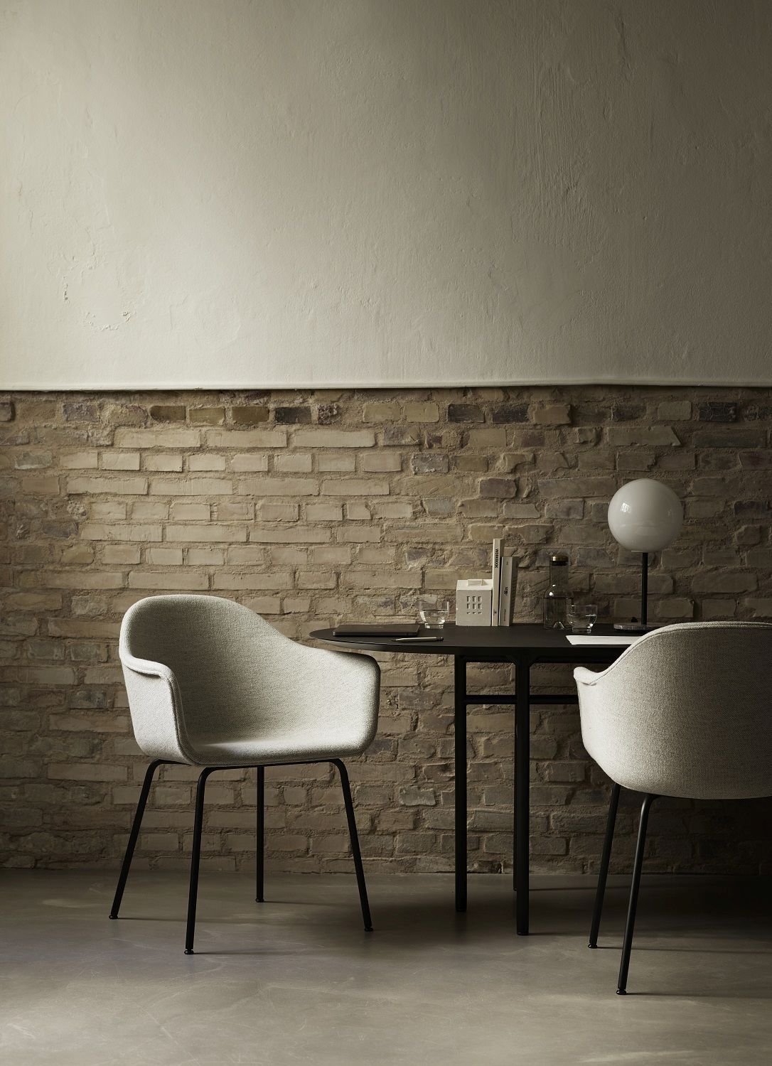Audo Copenhagen Harbour Dining Chair Stuhl in Grau am Esstisch vor Backsteinwand.