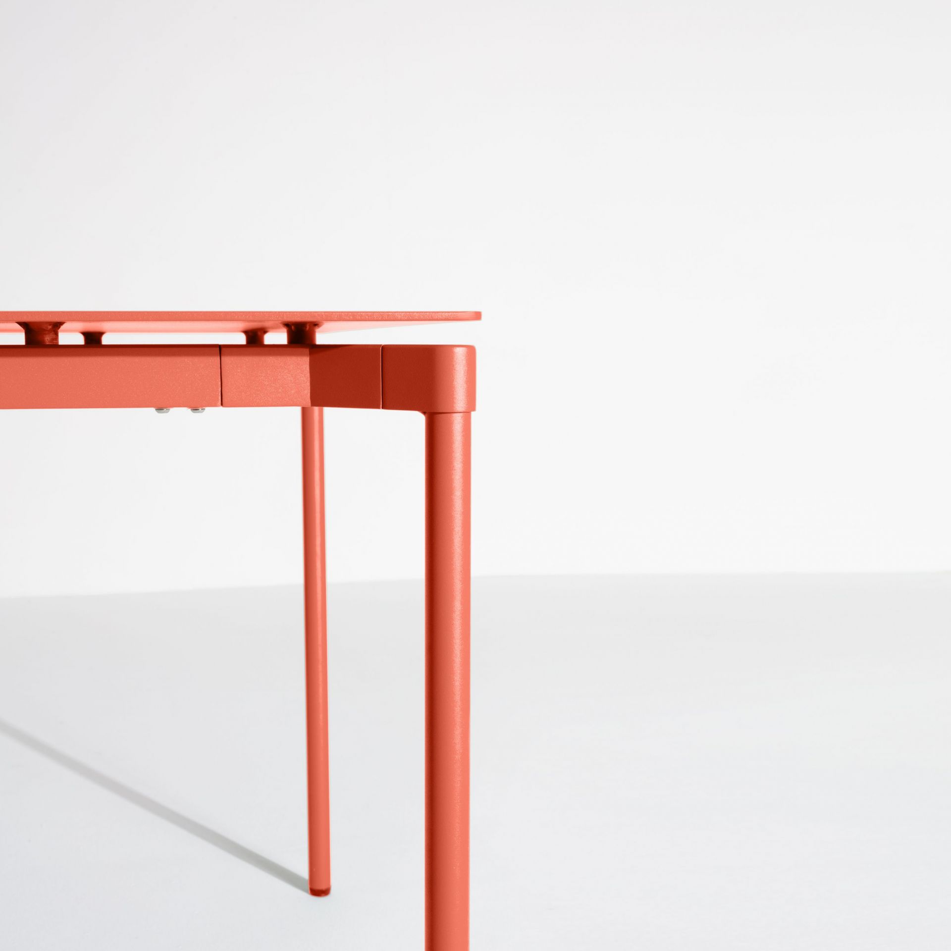 Detailaufnahme des korallfarbenen Fromme Esstisches von Petite Friture, rechteckig, mit minimalistischem Design und schlanken Beinen.