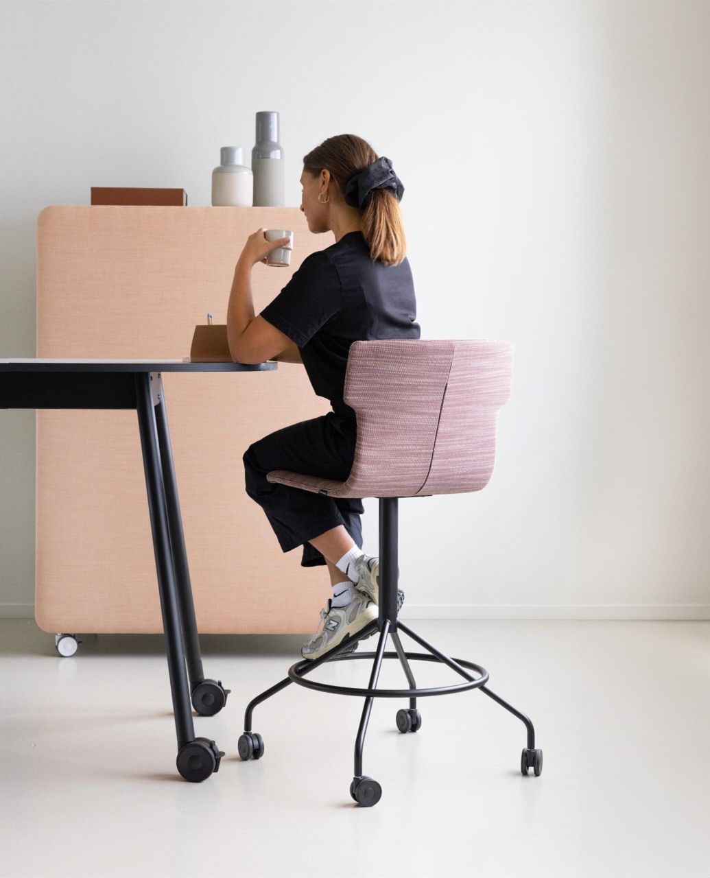 Frau sitzt auf einem rosa Cascando Co-Chair Bürodrehstuhl mit Rollen am Schreibtisch.