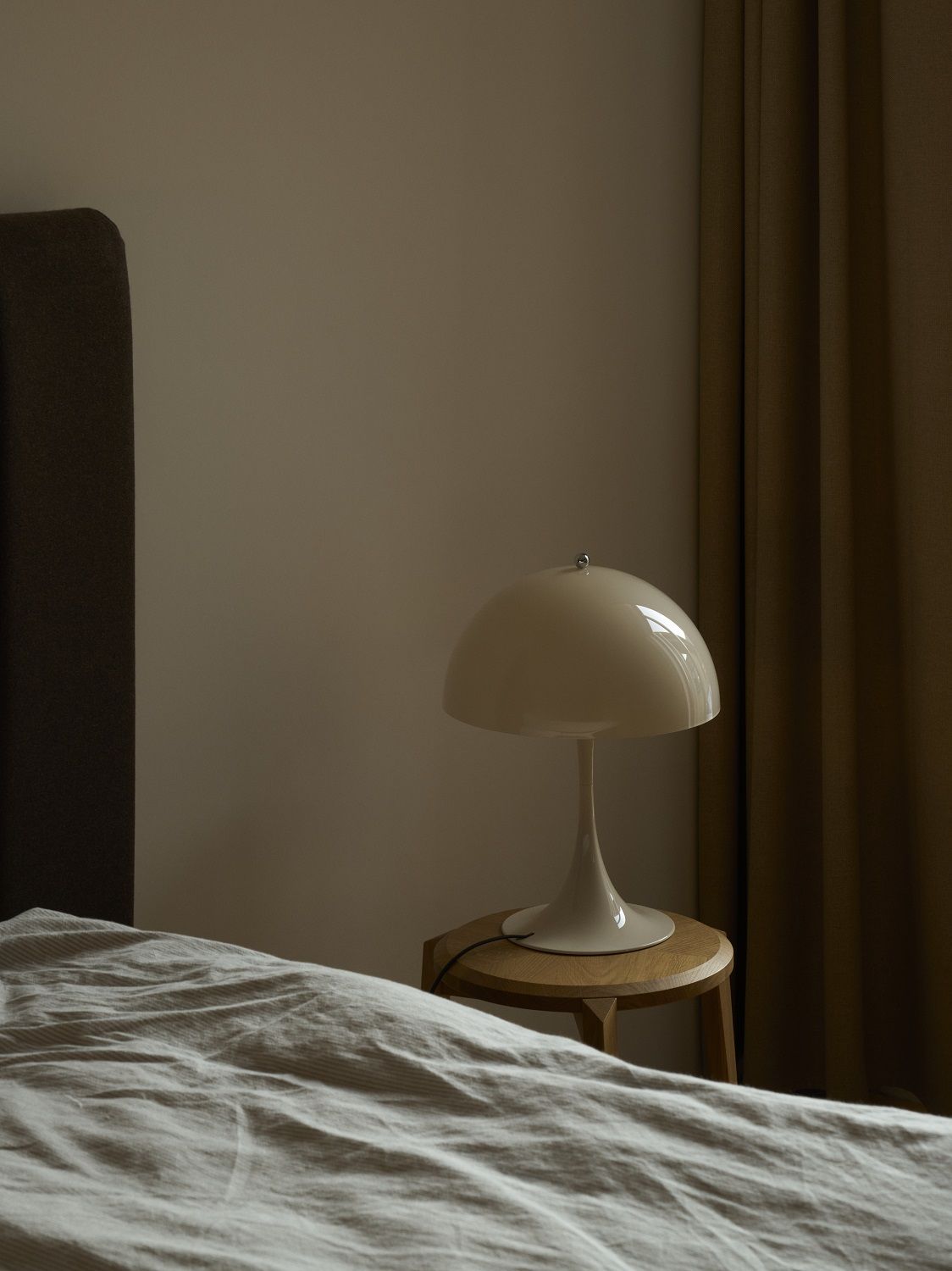 Panthella Tischleuchte in Opal Weiß auf Nachttisch neben Bett, modernes Design für Schlafzimmerbeleuchtung.