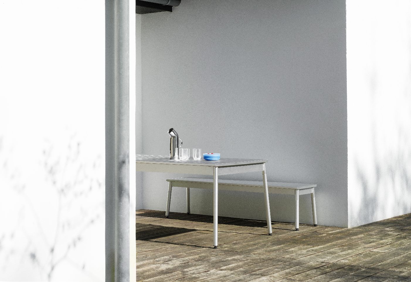 Normann Copenhagen Ex Tisch für den Außenbereich mit passender Bank auf einer Holzterrasse.