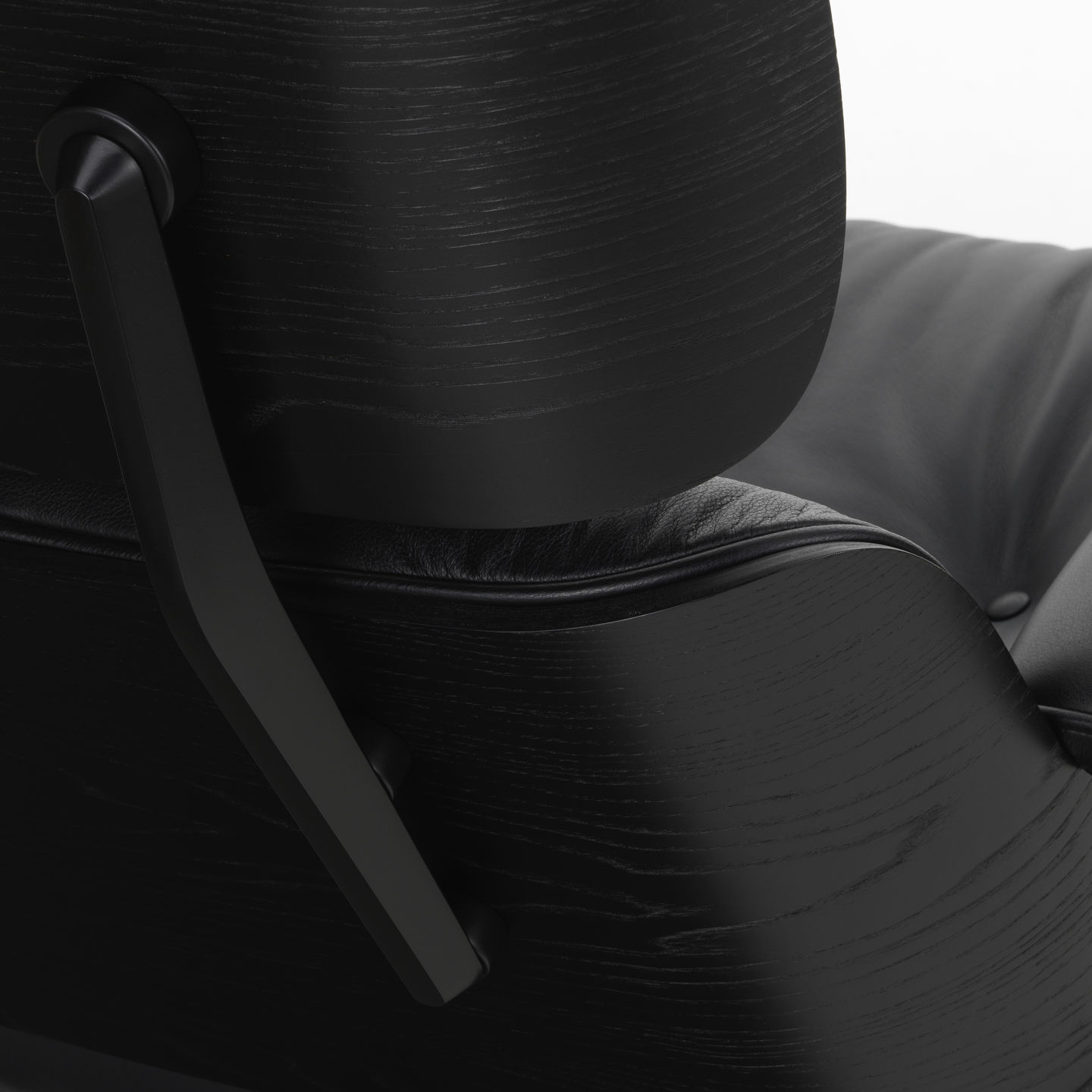 Detailaufnahme des schwarzen Eames Lounge Chair Sessels von Vitra mit Lederpolsterung und Holzstruktur.