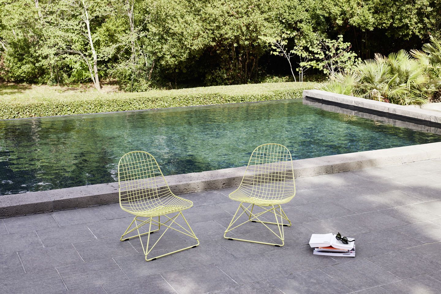 Zwei gelbe Vitra Wire Chairs LKR-2 mit Sitzbezug am Pool, moderne Gartenmöbel.