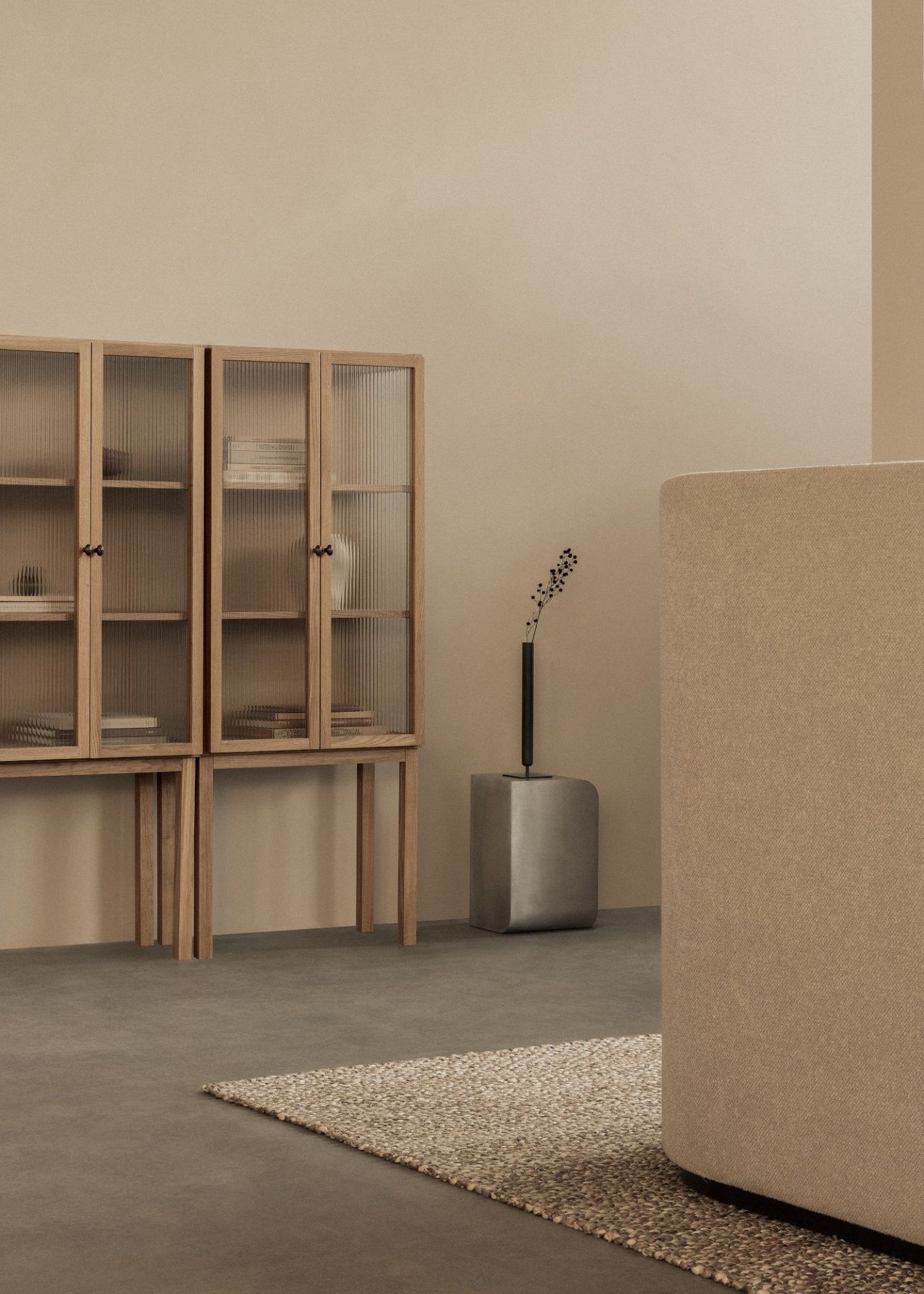 Audo Copenhagen Curiosity Cabinet Low, ein Holzschrank mit geriffelten Glastüren im minimalistischen Wohnzimmer.