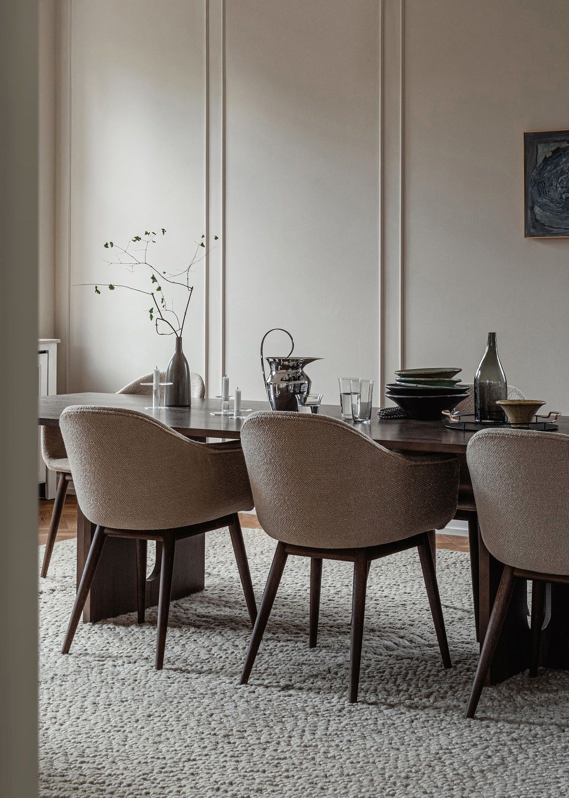 Detailaufnahme des Audo Copenhagen Gravel Rug Teppichs unter einem Esstisch mit Stühlen und Geschirr.
