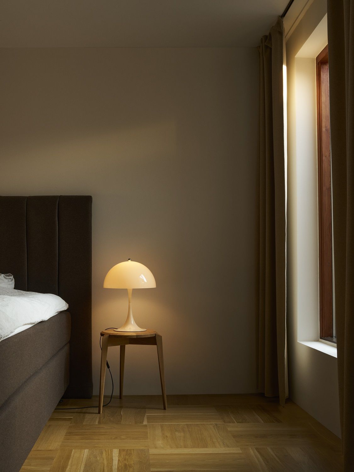 Panthella 320 Tischleuchte in Opal Weiß von Louis Poulsen auf Nachttisch neben Bett.