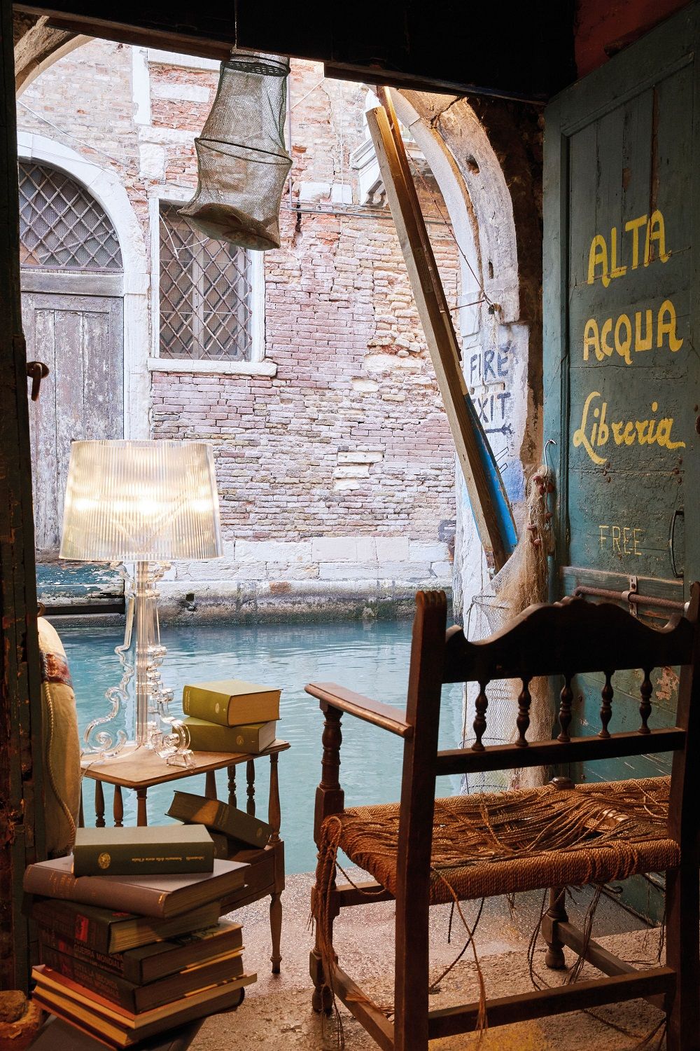 Bourgie Tischleuchte Glasklar von Kartell, dimmbare Designlampe auf einem Tisch mit Büchern in Venedig.