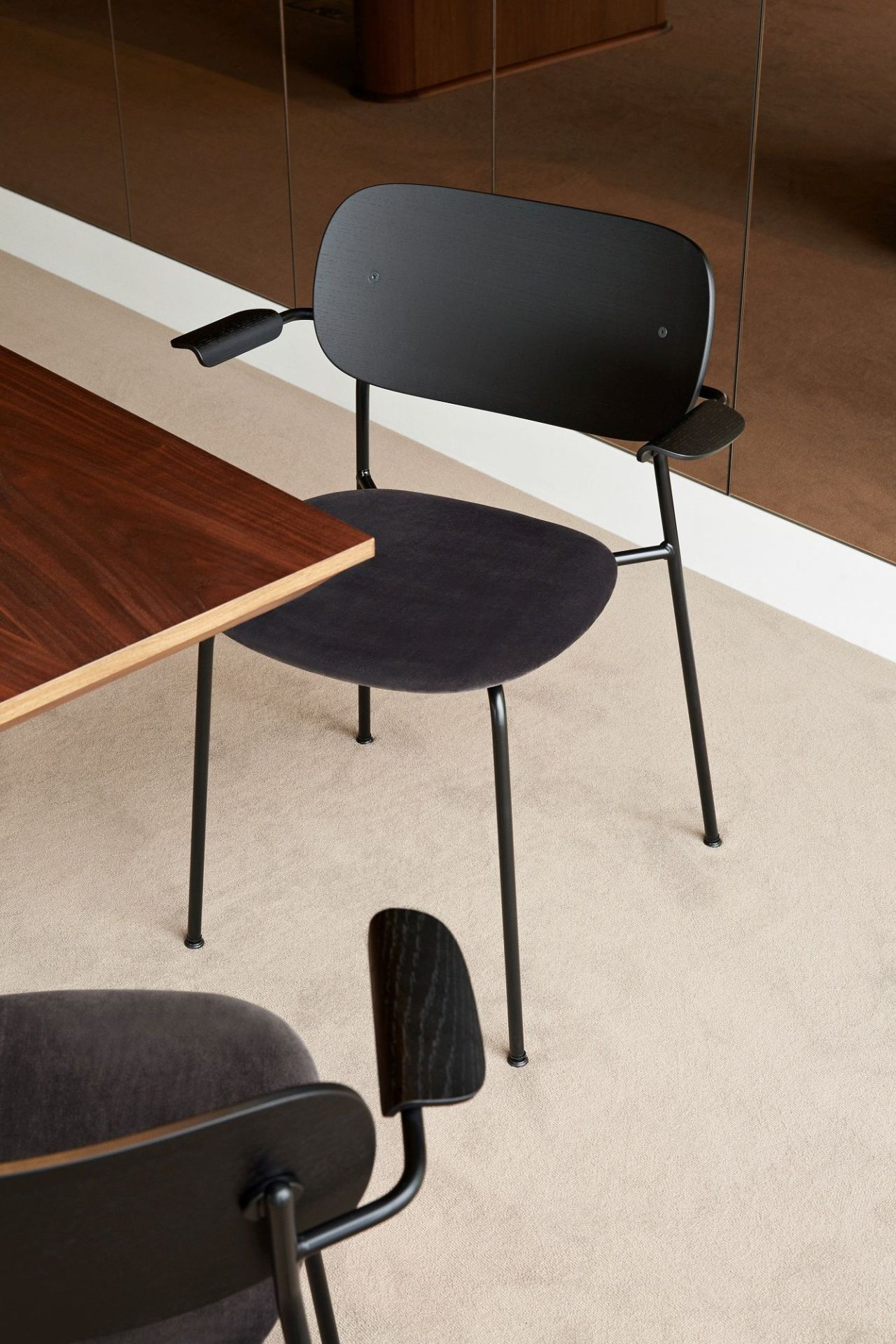 Audo Copenhagen Co Dining Chair Stuhl in Schwarz mit Armlehnen am Esstisch.