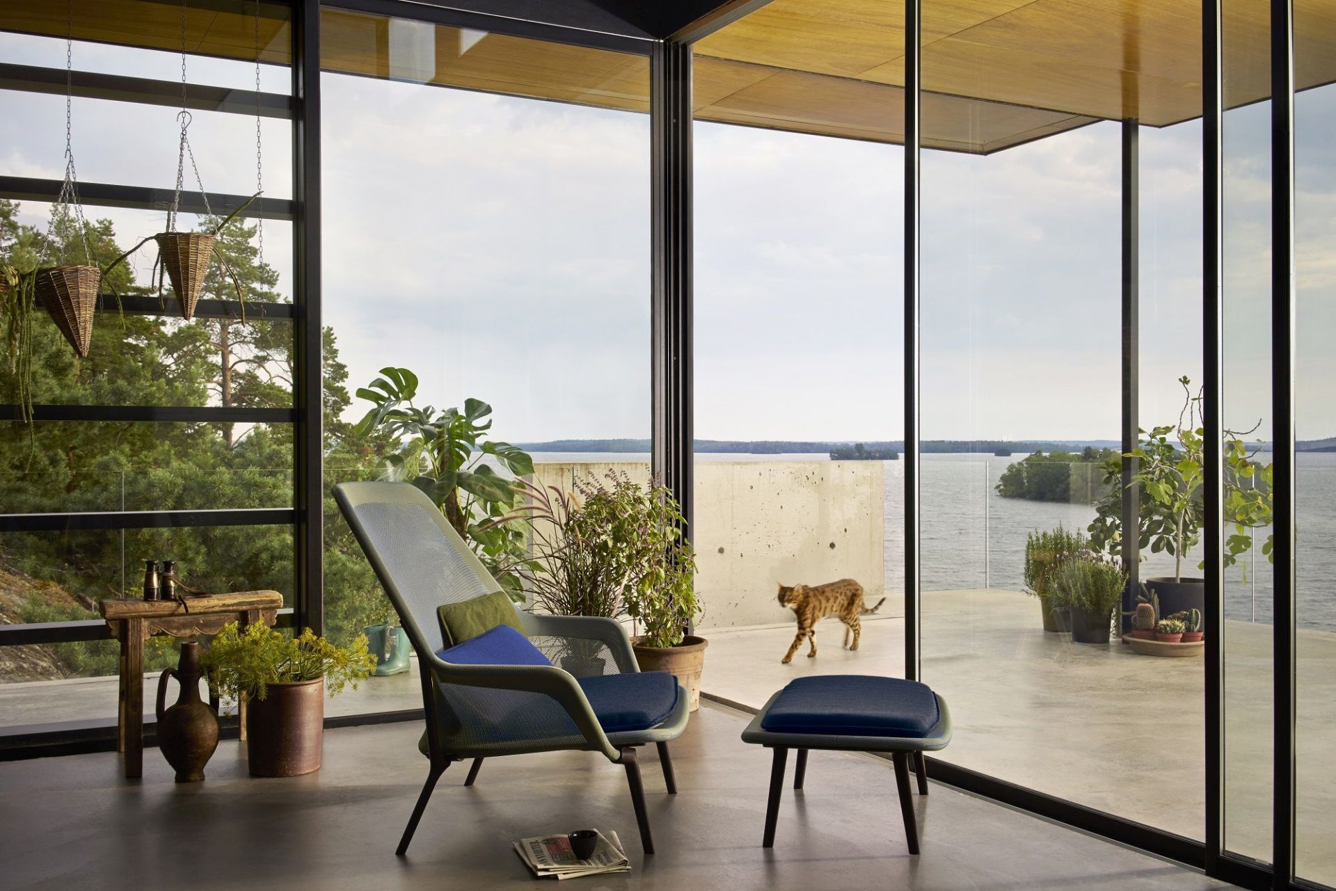 Vitra Slow Chair Sessel mit Hocker in modernem Wohnraum mit Seeblick und Katze.