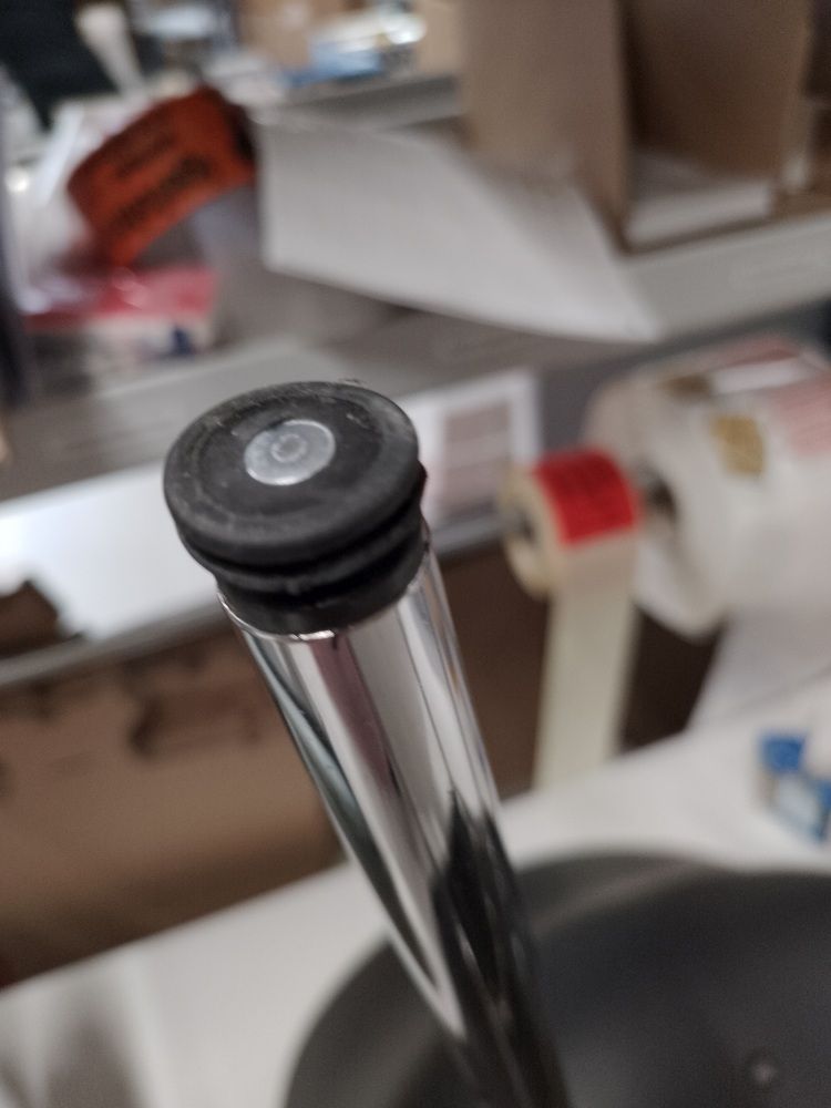 Detailaufnahme vom Fuß eines HAY About A Chair AAC26 Stuhls mit Chromgestell und schwarzem Fußgleiter.