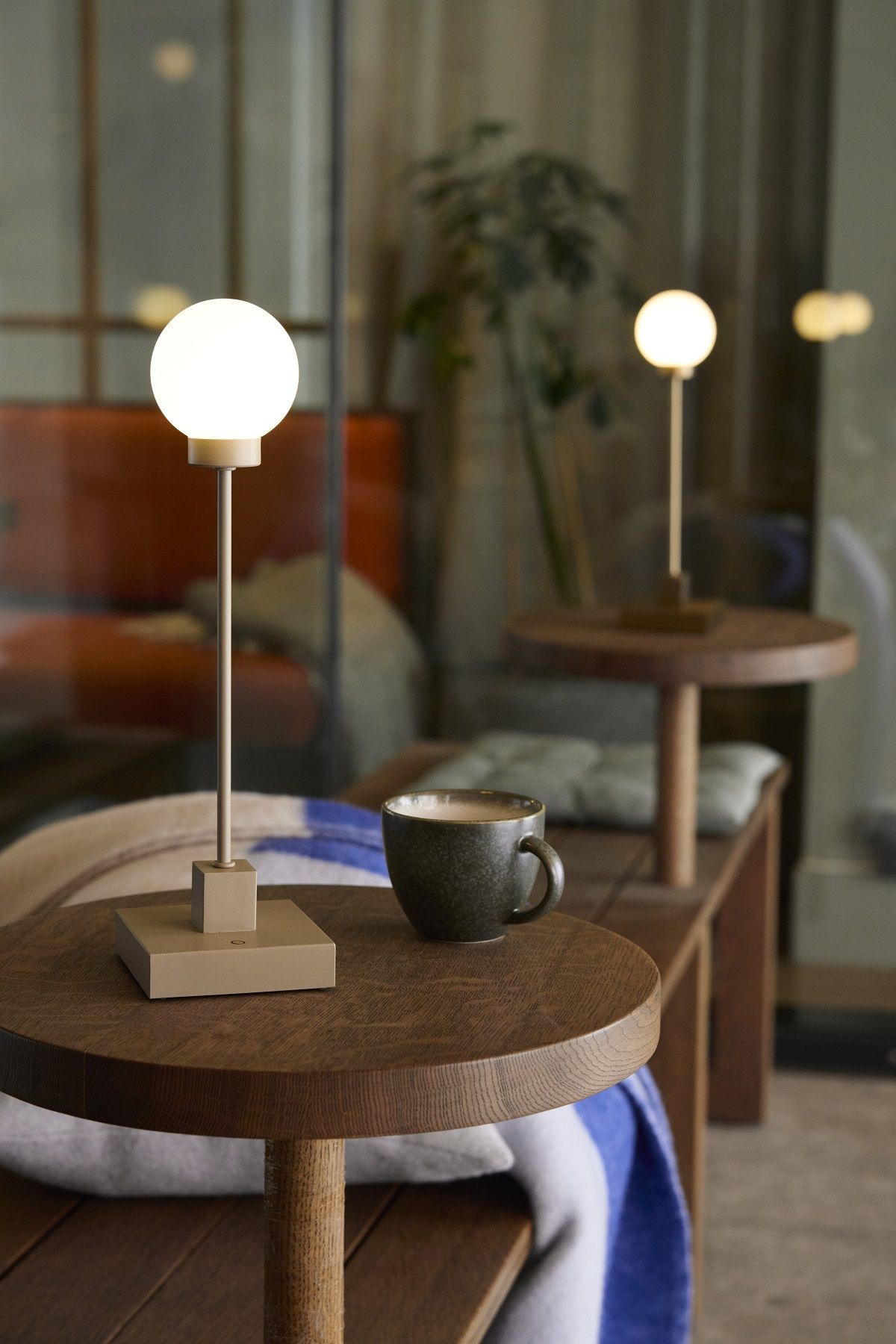 Snowball Tischleuchte von Northern auf einem Holztisch mit Kaffeetasse, gemütliche Atmosphäre.