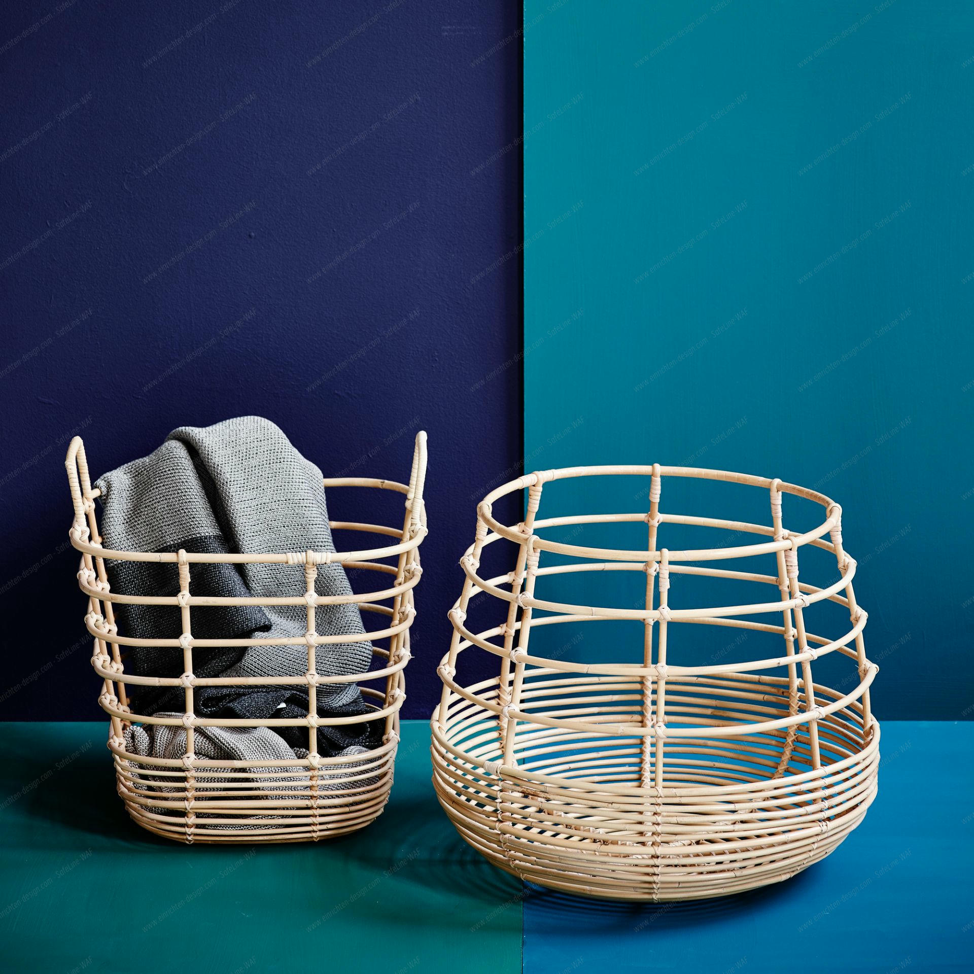 Zwei Cane-Line Sweep Körbe aus Rattan, einer mit Decke, vor blauem Hintergrund.