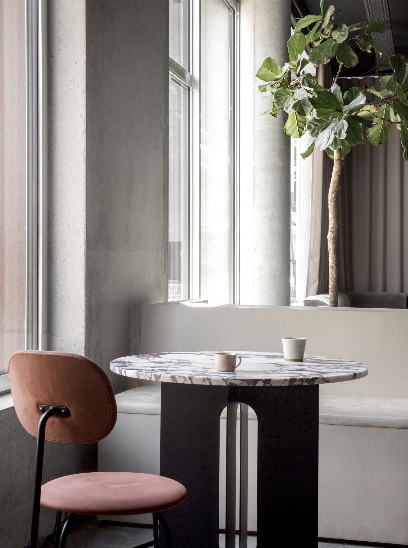 Nahaufnahme eines Afteroom Dining Chair Plus Stuhls in Rosa, mit Marmortisch und Tassen in modernem Ambiente.