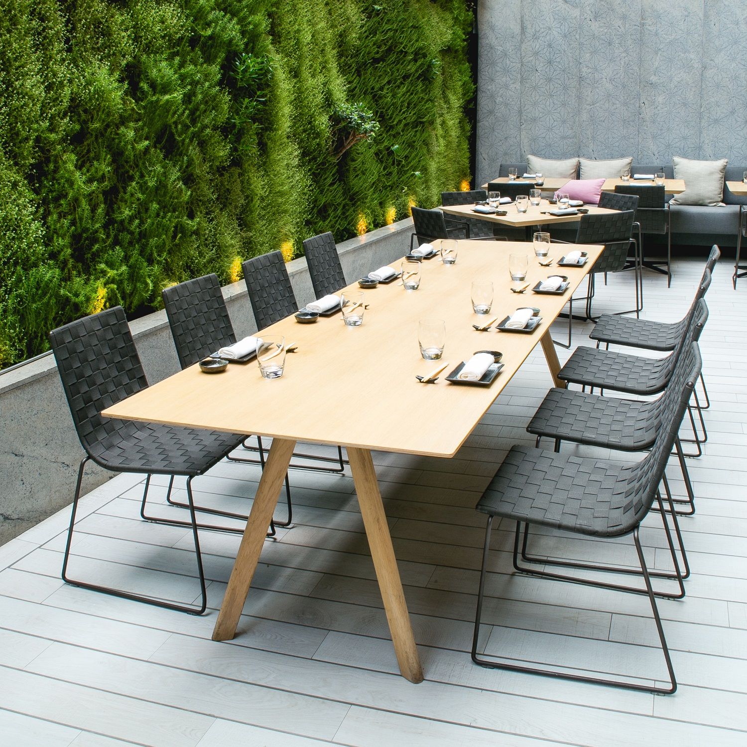 Andreu World Trenza Stuhl SI0700, stapelbarer Outdoor-Stuhl mit geflochtener Sitzfläche und schwarzem Metallgestell.