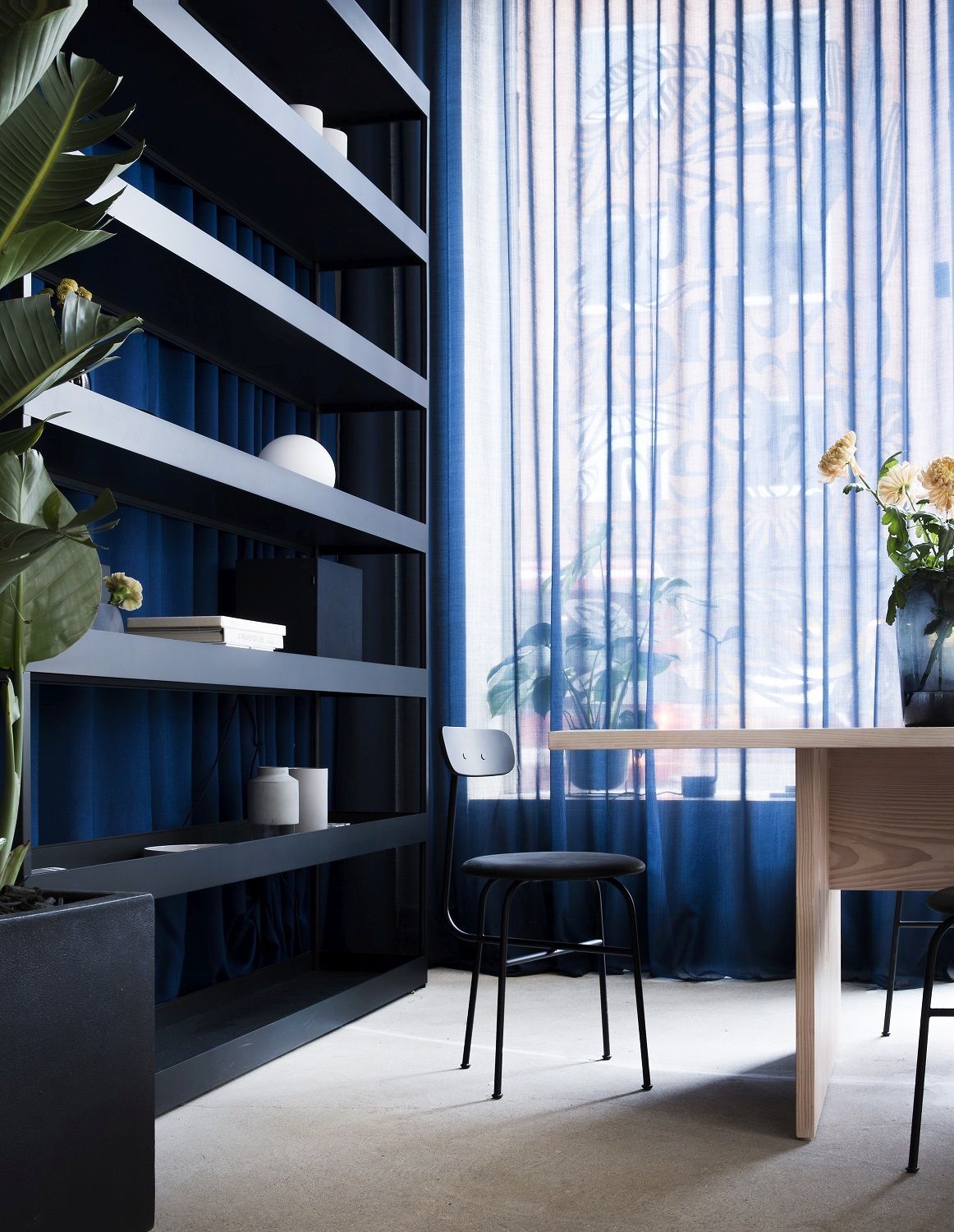 Schwarzer Afteroom Stuhl von Audo Copenhagen in modernem Esszimmer mit Tisch und Regal.