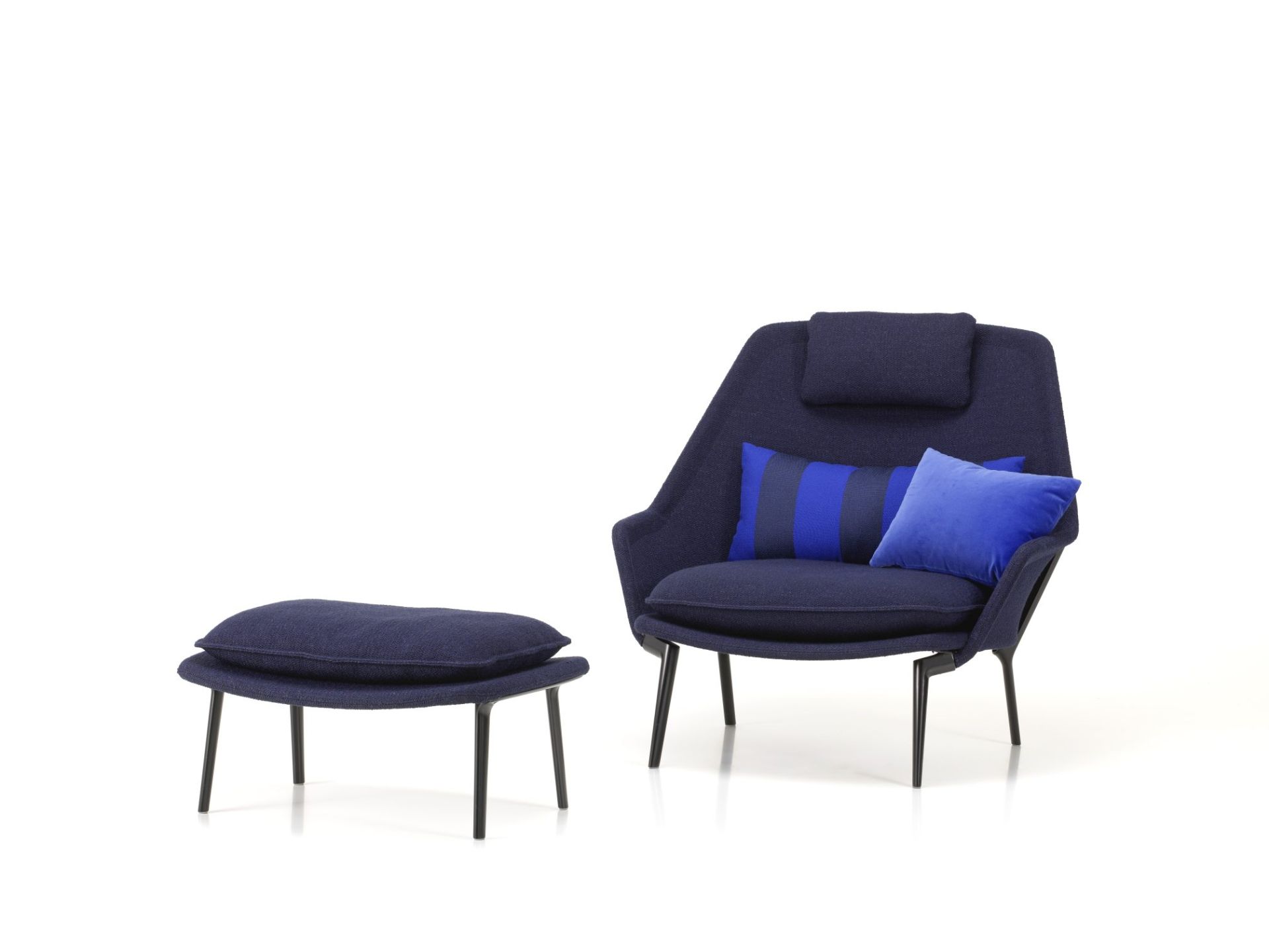 Vitra Slow Chair Sessel mit Ottoman in blauem Stoff und Kissen auf weißem Hintergrund.
