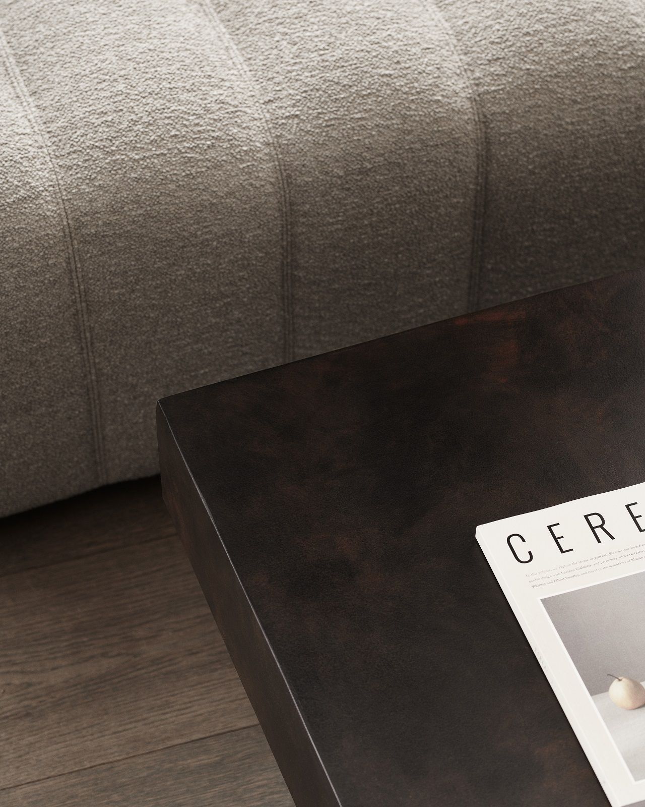 Detailaufnahme des Gear Square Couchtischs von Norr11 in dunklem Holz neben einem grauen Sofa.
