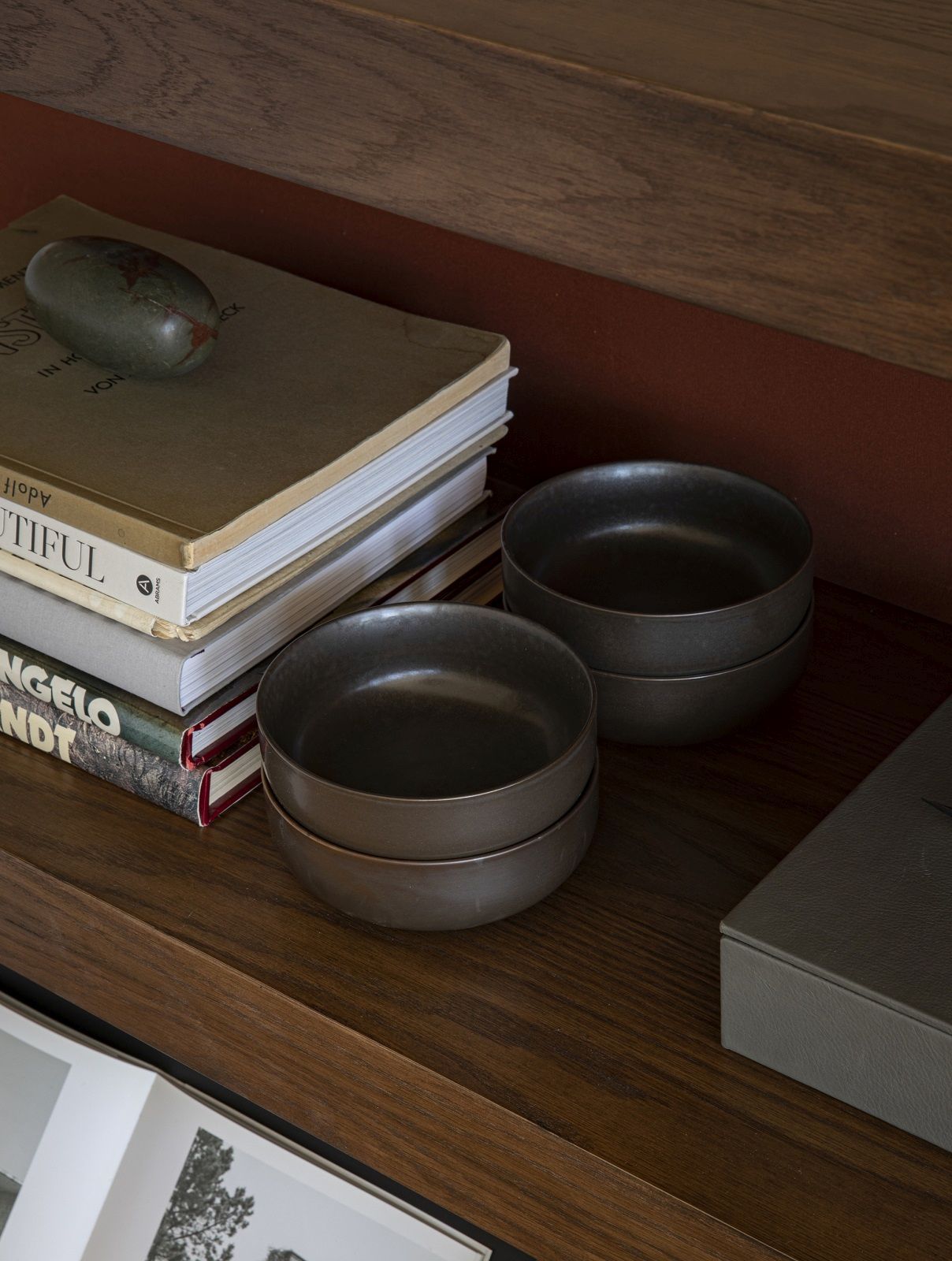 Detailaufnahme: Audo Copenhagen Zet Storage System Regal mit Büchern und Schalen auf einer Holzoberfläche.