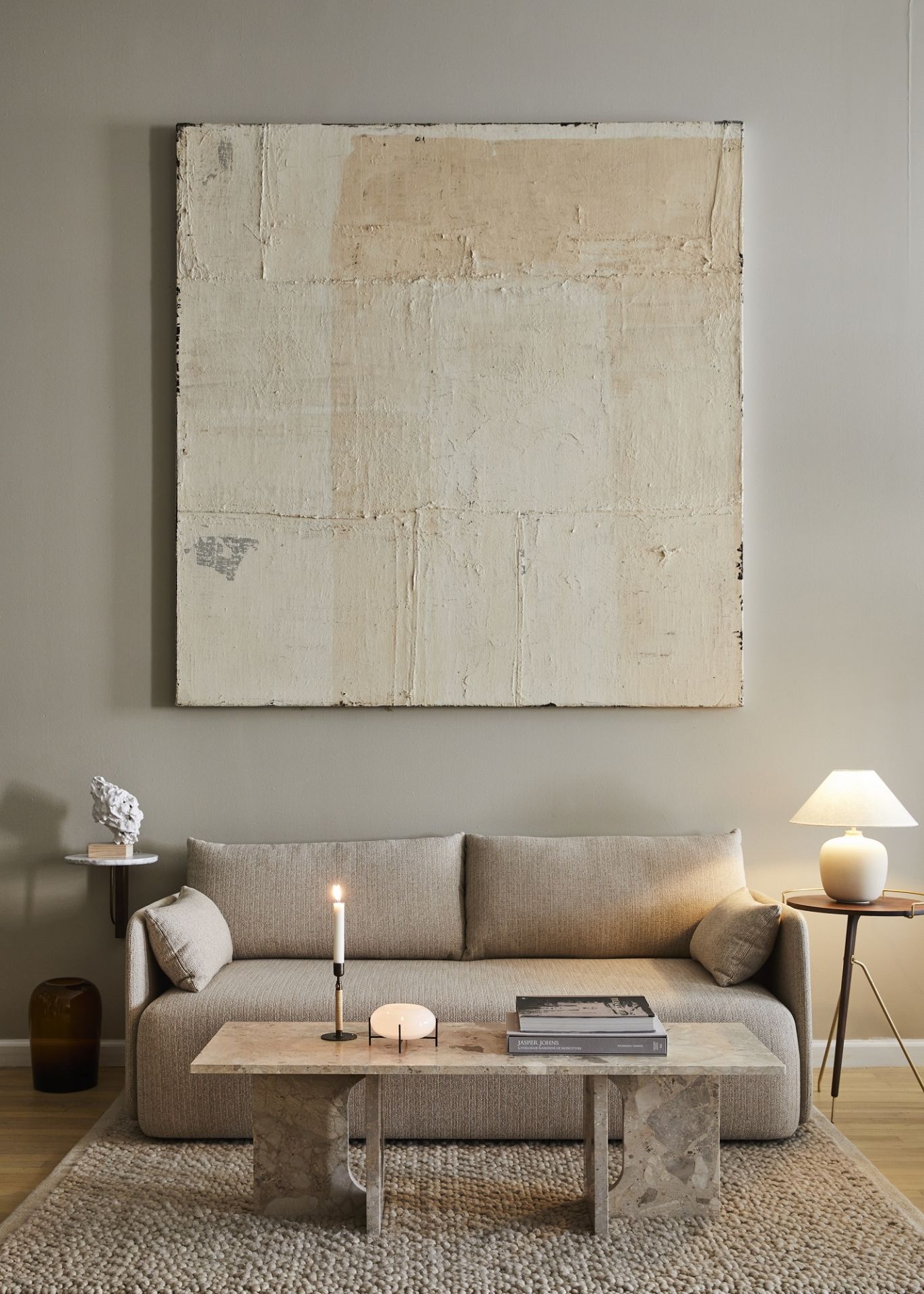 Androgyne Couchtisch von Audo Copenhagen aus Travertin in stilvollem Wohnzimmer mit Sofa und Teppich.