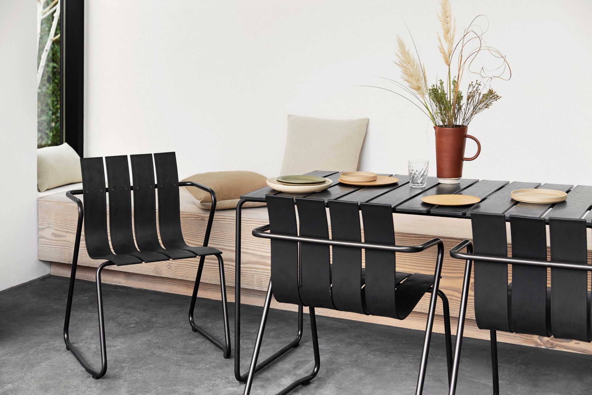 Schwarzer Ocean Tisch mit vier Stühlen für den Außenbereich, modernes Design mit Tellern und Dekoration.