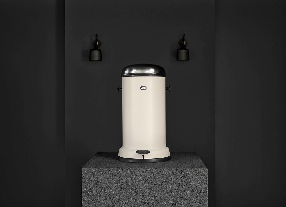 Beige Vipp Treteimer, 8 Liter, aus Stahl und mit Pedal auf einem grauen Sockel.