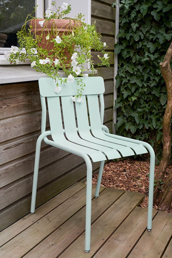 Mintfarbener Stripe Chair Stuhl von Fermob für den Außenbereich auf einer Holzterrasse.