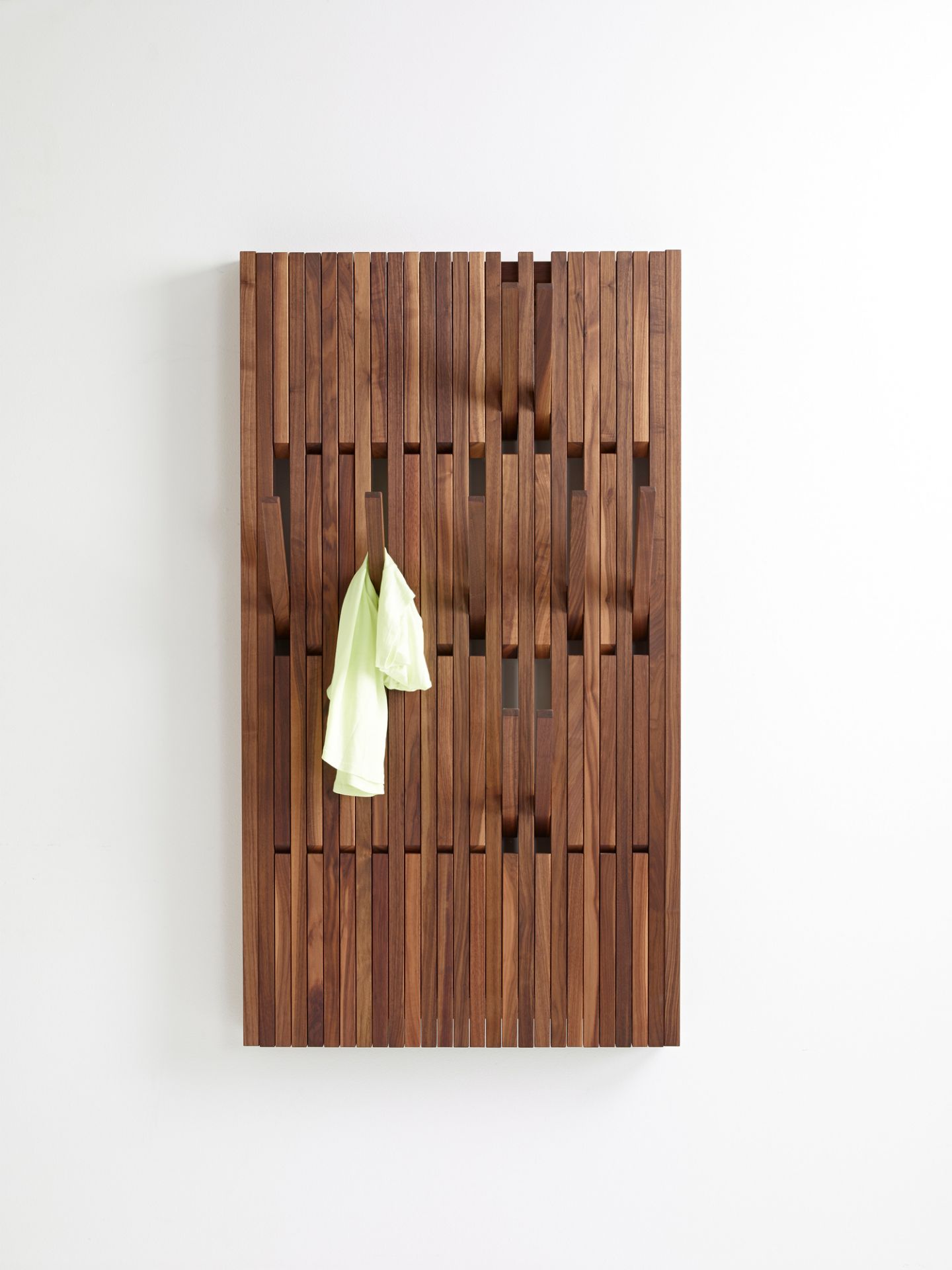 Piano Wandgarderobe aus Walnussholz, geölt, mit hochklappbaren Haken und einem hellen T-Shirt.
