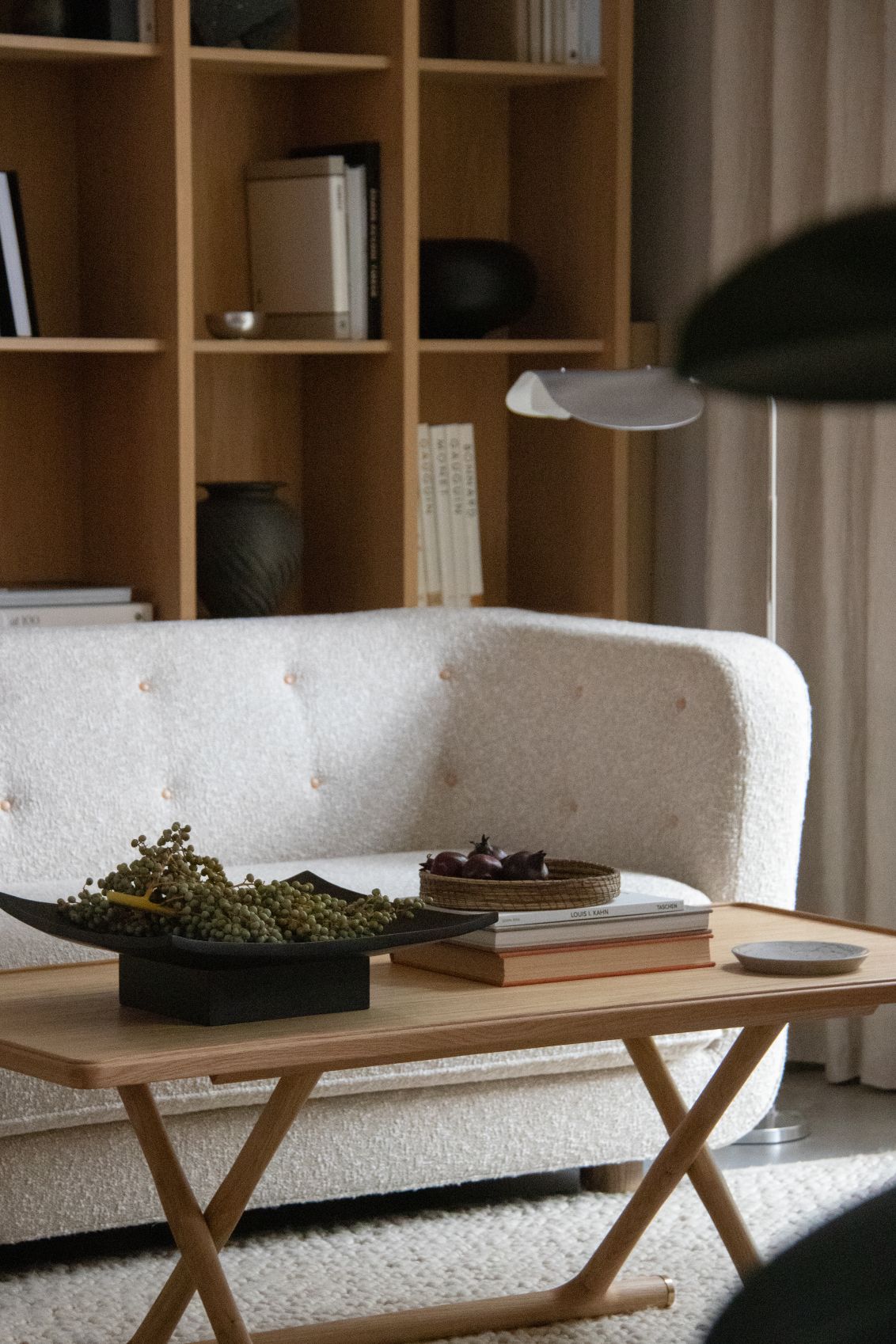 Audo Copenhagen Relevé Platte in Schwarz auf einem Holztisch mit Deko-Elementen in Wohnzimmer-Szene.