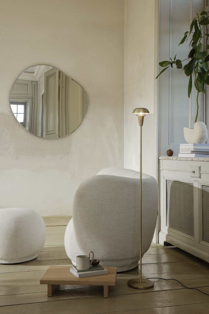 Nahaufnahme der goldenen Ferm Living Tiny Floor Lamp Stehleuchte in einem stilvollen Wohnzimmer mit Sessel.