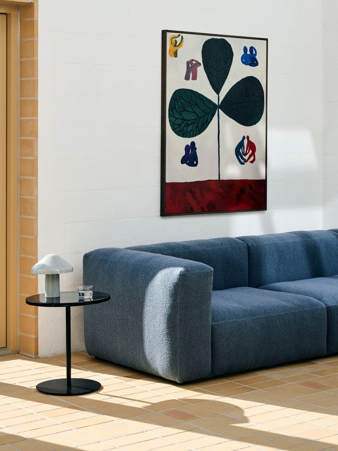 Schwarzer Hay Pyro Coffee Table im Wohnzimmer neben blauem Sofa und Kunstwerk an der Wand.