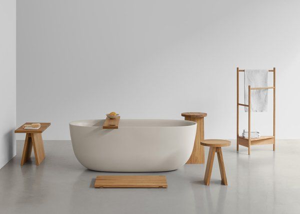 E15 Hocker EK06 aus Holz neben Badewanne, Handtuchhalter und Bad-Accessoires für stilvolles Badezimmer.