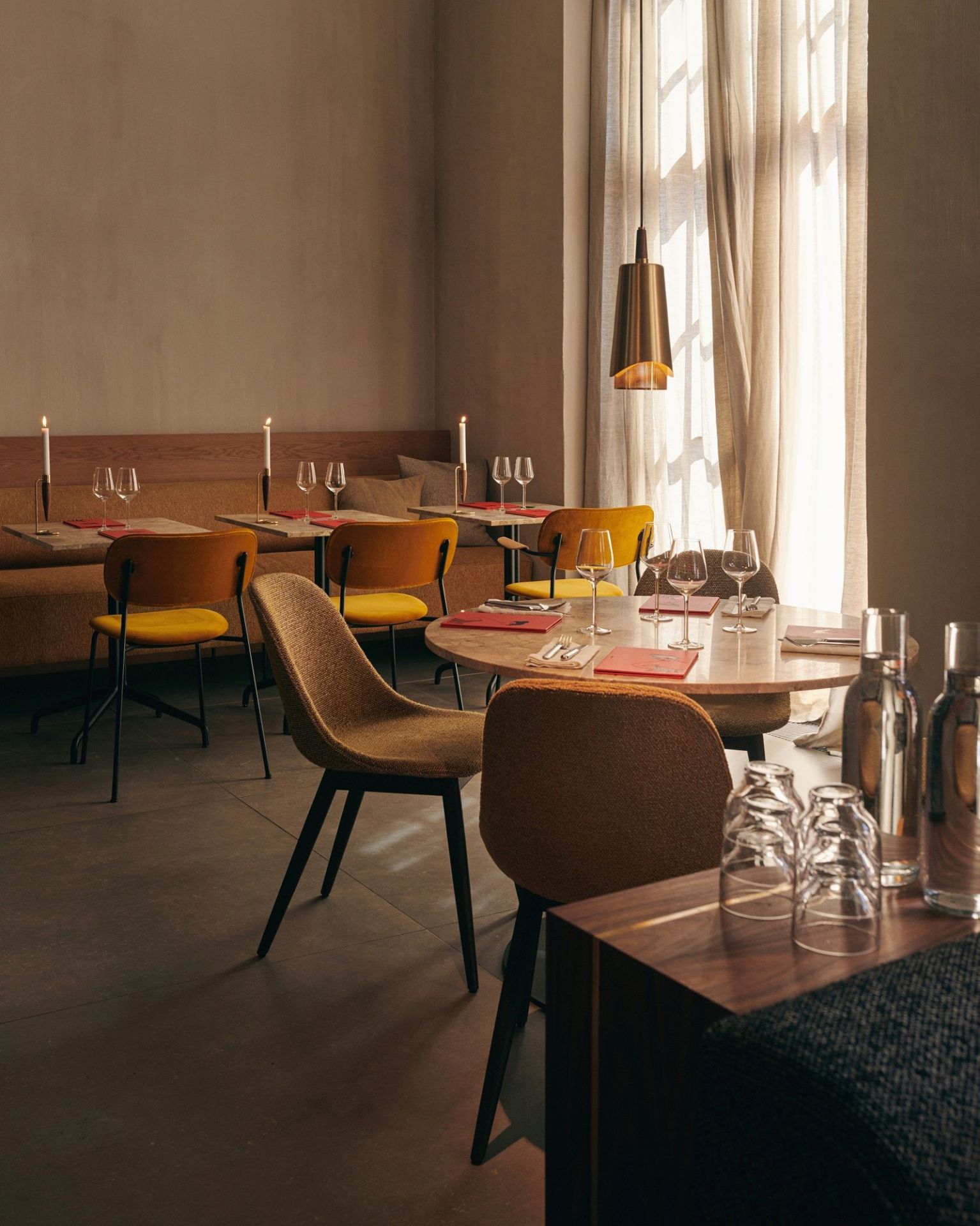 Innenaufnahme eines Restaurants mit Audo Copenhagen Harbour Side Dining Chairs und gedeckten Tischen.