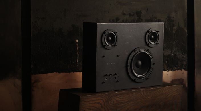 Schwarzer Stahl Lautsprecher auf Holzsockel vor dunklem Hintergrund, Nahaufnahme für Hi-Fi-Enthusiasten.