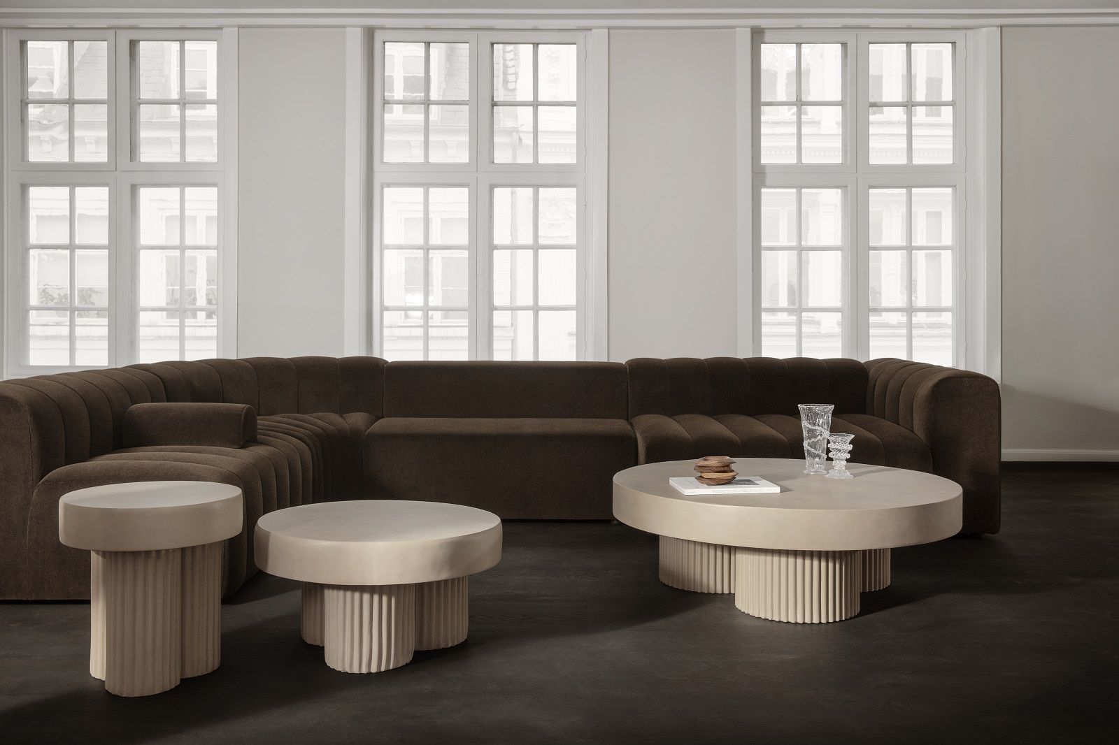 Gear Round Couchtisch von Norr11, runde Form mit geriffelter Basis, modernes Wohnzimmer-Interieur mit braunem Sofa.