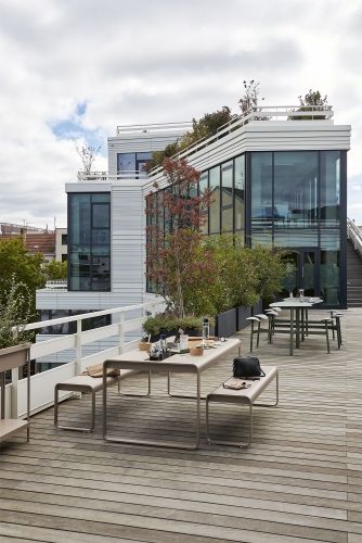 Bolder 3-Sitzer-Tisch mit Sitzflächen von Fermob, ideal für stilvolle Outdoor-Bereiche auf einer Dachterrasse.