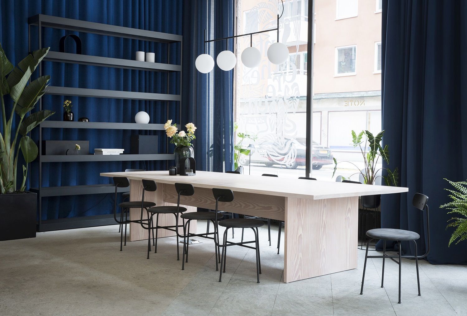 Innenaufnahme eines hellen Esszimmers mit großem Holztisch und schwarzen Afteroom Dining Chairs von Audo Copenhagen.