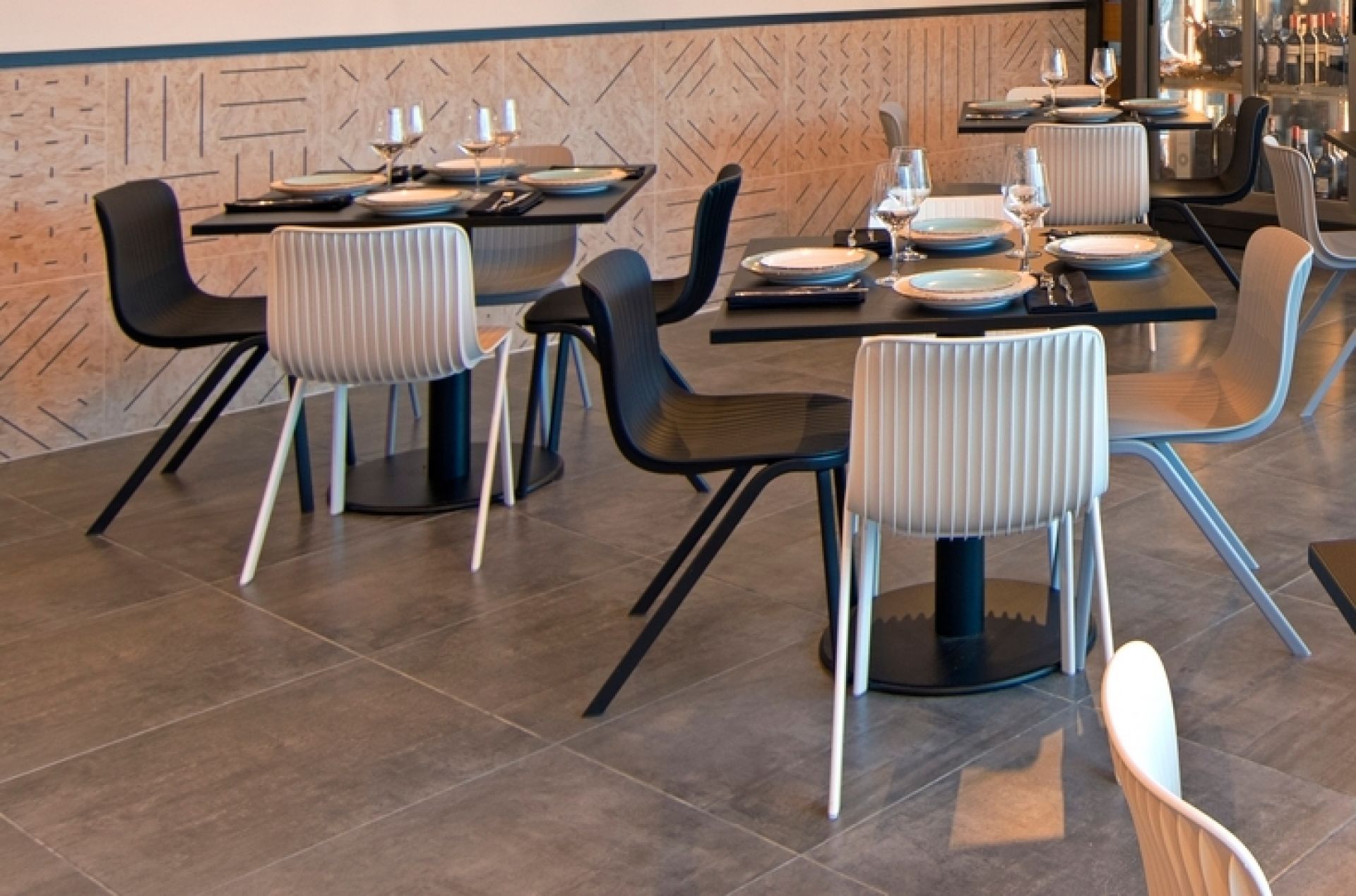 Schwarzer Dragonfly Stuhl von Segis mit Metallbeinen an gedecktem Tisch in einem Restaurant.