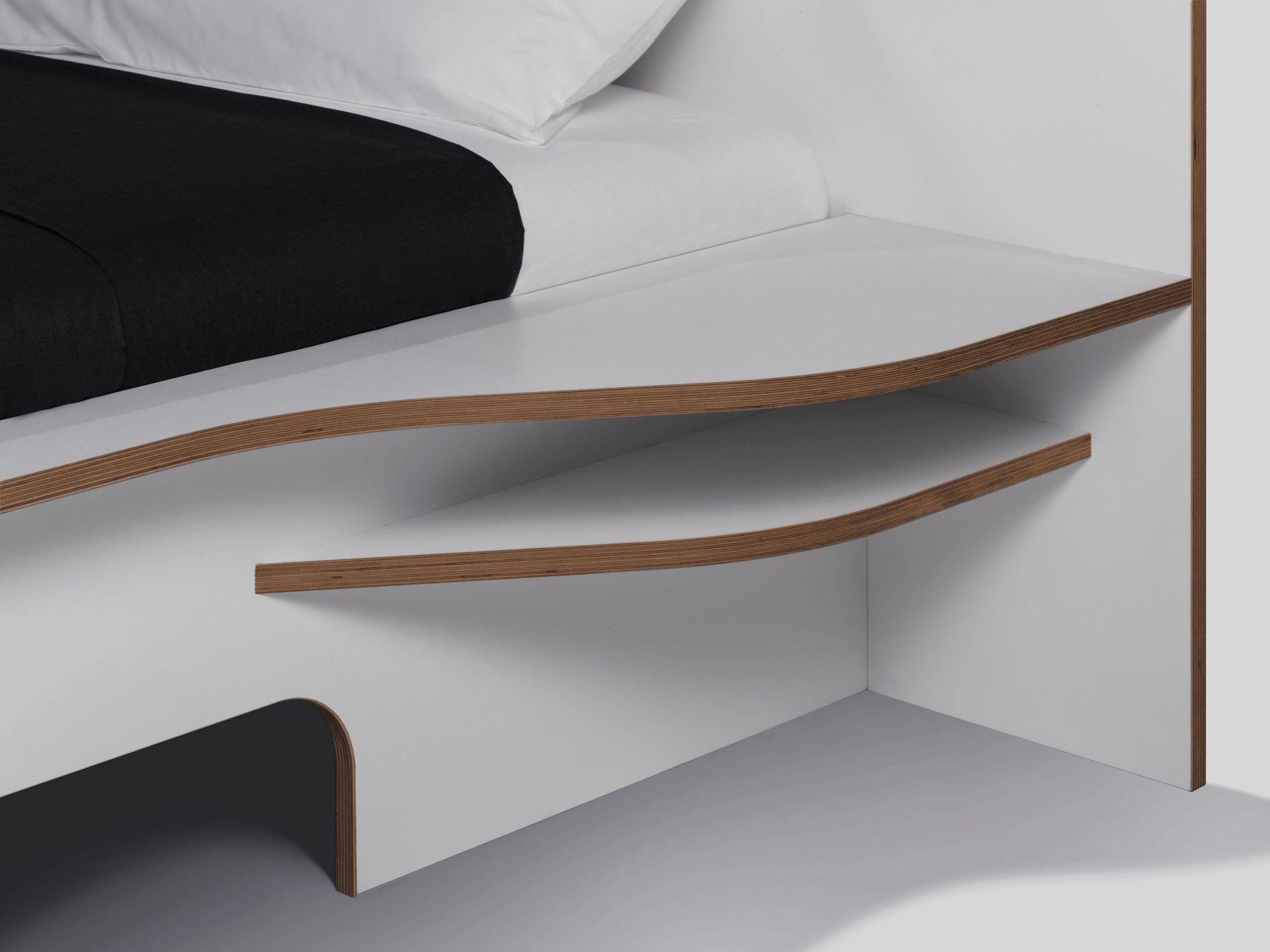 Detailaufnahme vom weißen Plane Doppelbett von Müller Möbelwerkstätten mit Ablagefächern aus Holz.